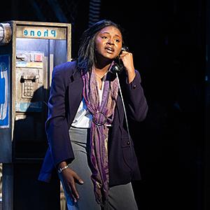female actor on stage using phone booth