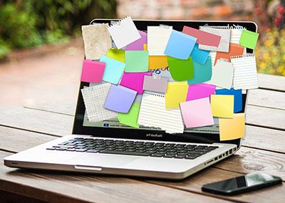 A laptop fully covered in colorful sticky notes